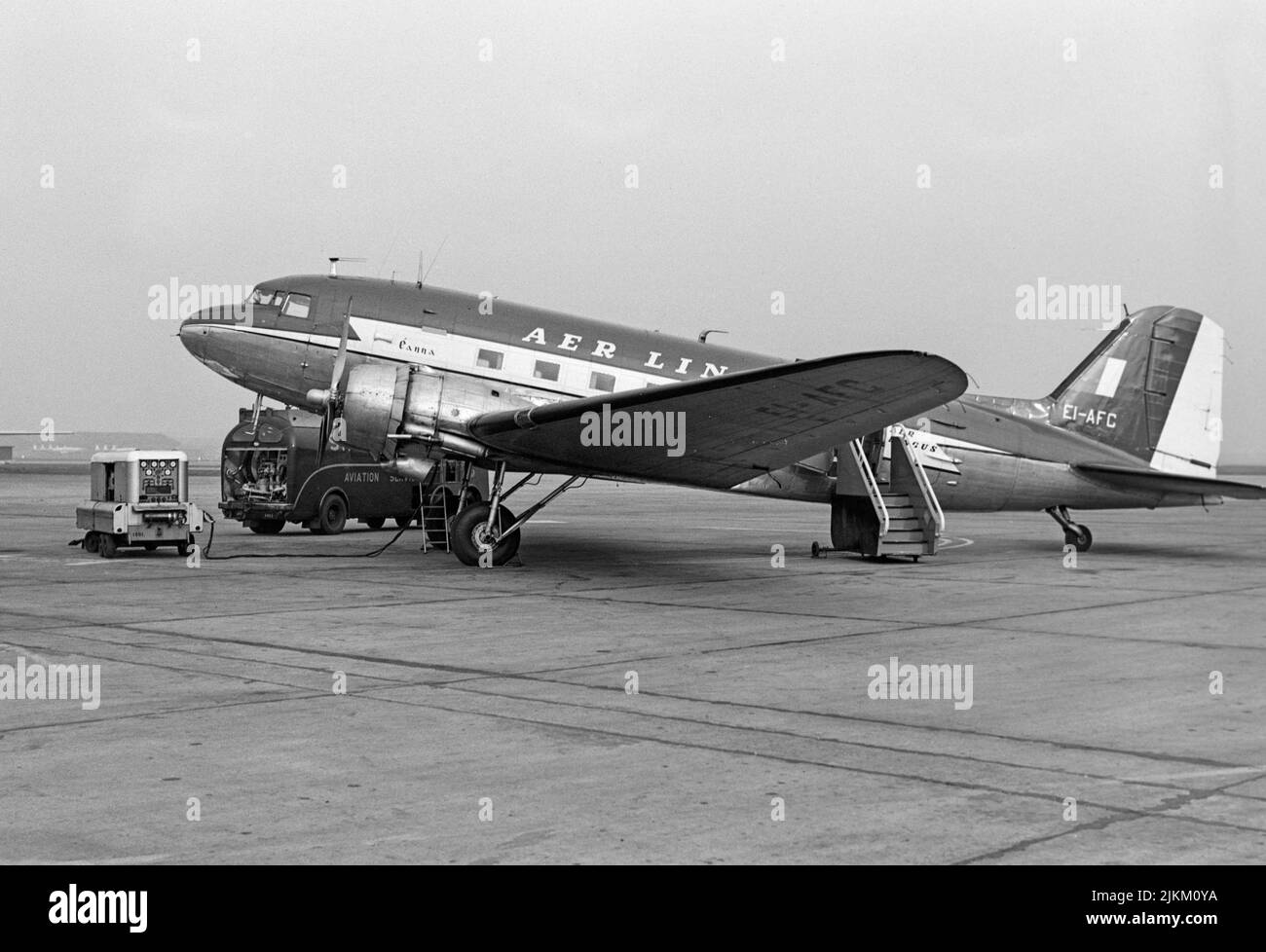 A vintage 1960s black and white photograph of an Are Lingus Douglas DC-3, C-47, airliner. Registration EI-AFC. Aircraft is on the tarmac at an airport in England, with the passenger stairs at the rear door. Stock Photo