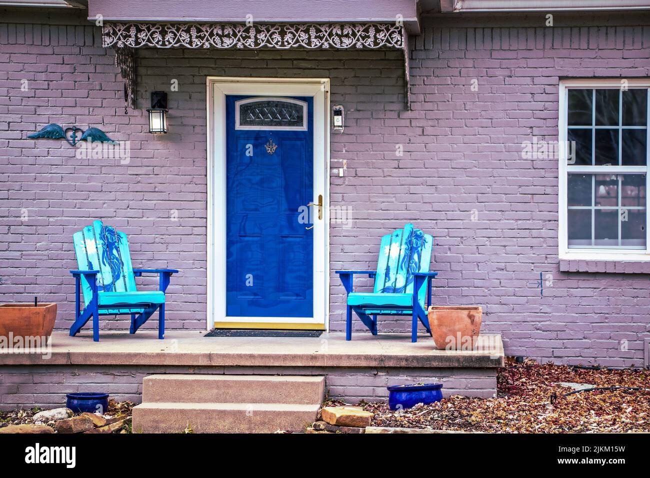 Blue mermaid adirondack chairs sit on porch of brick house painted
