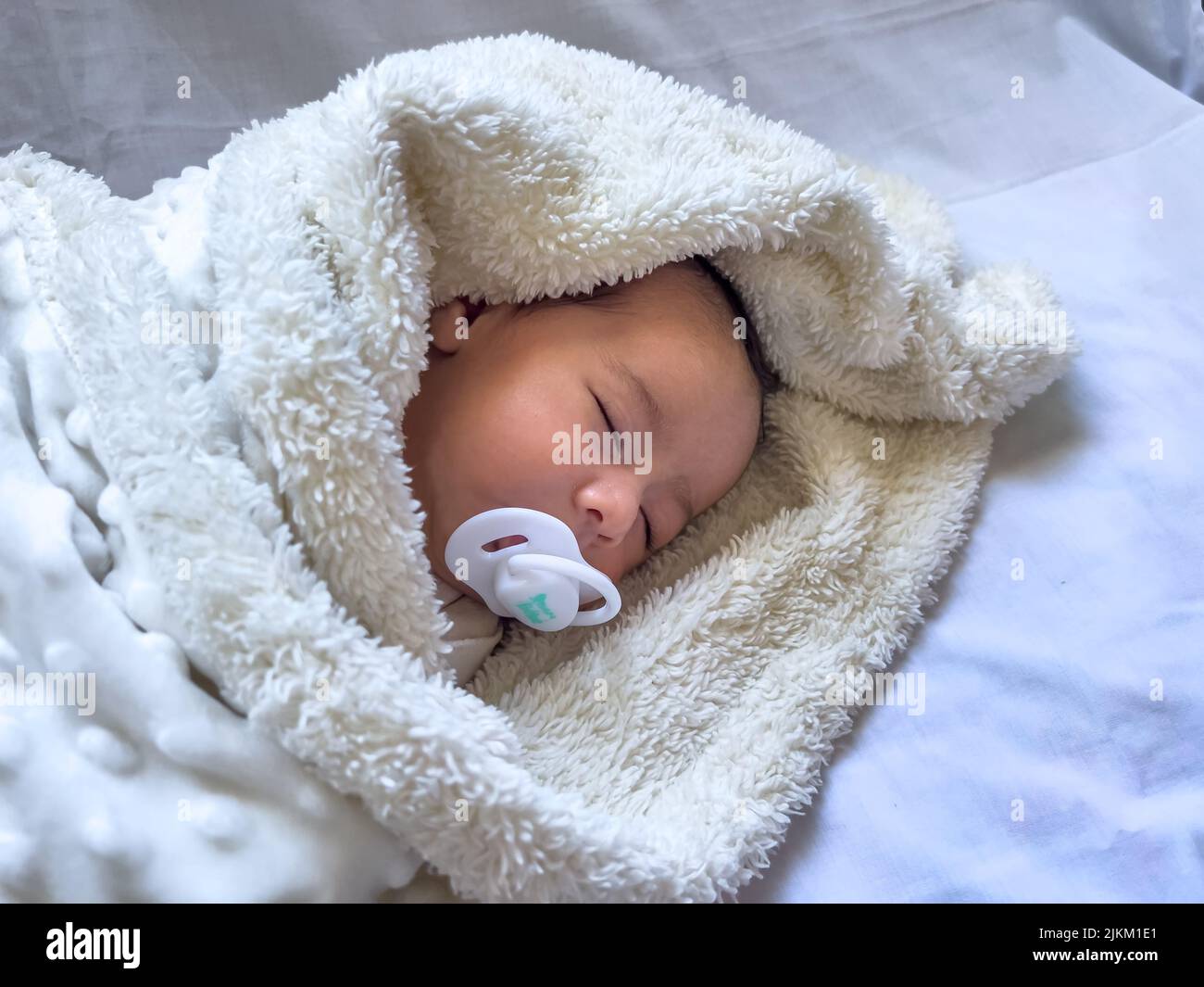 Sweet peaceful baby lying on a white bedsheet enjoy daytime slumber Stock Photo