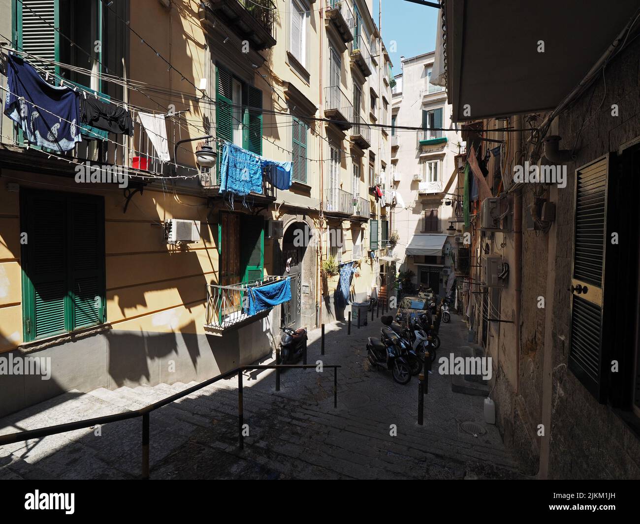 Typical street in Naples city center, steep and narrow with laundry hanging out to dry, and many scooters, Napoli, Campania, Italy Stock Photo