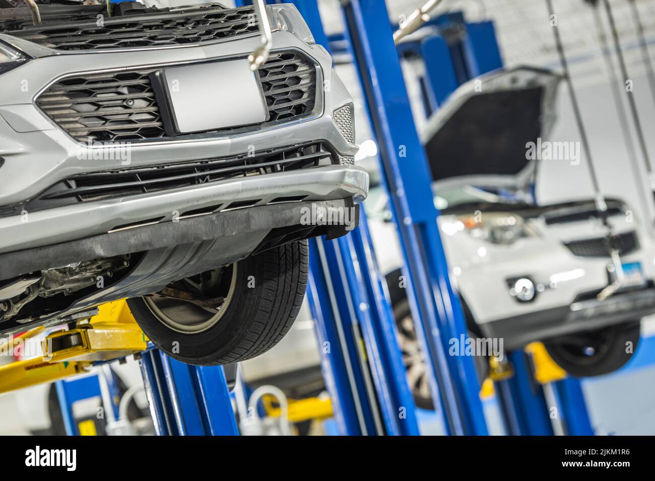 Modern Compact Cars Under Repair and Maintenance on a Lifts Inside Auto
