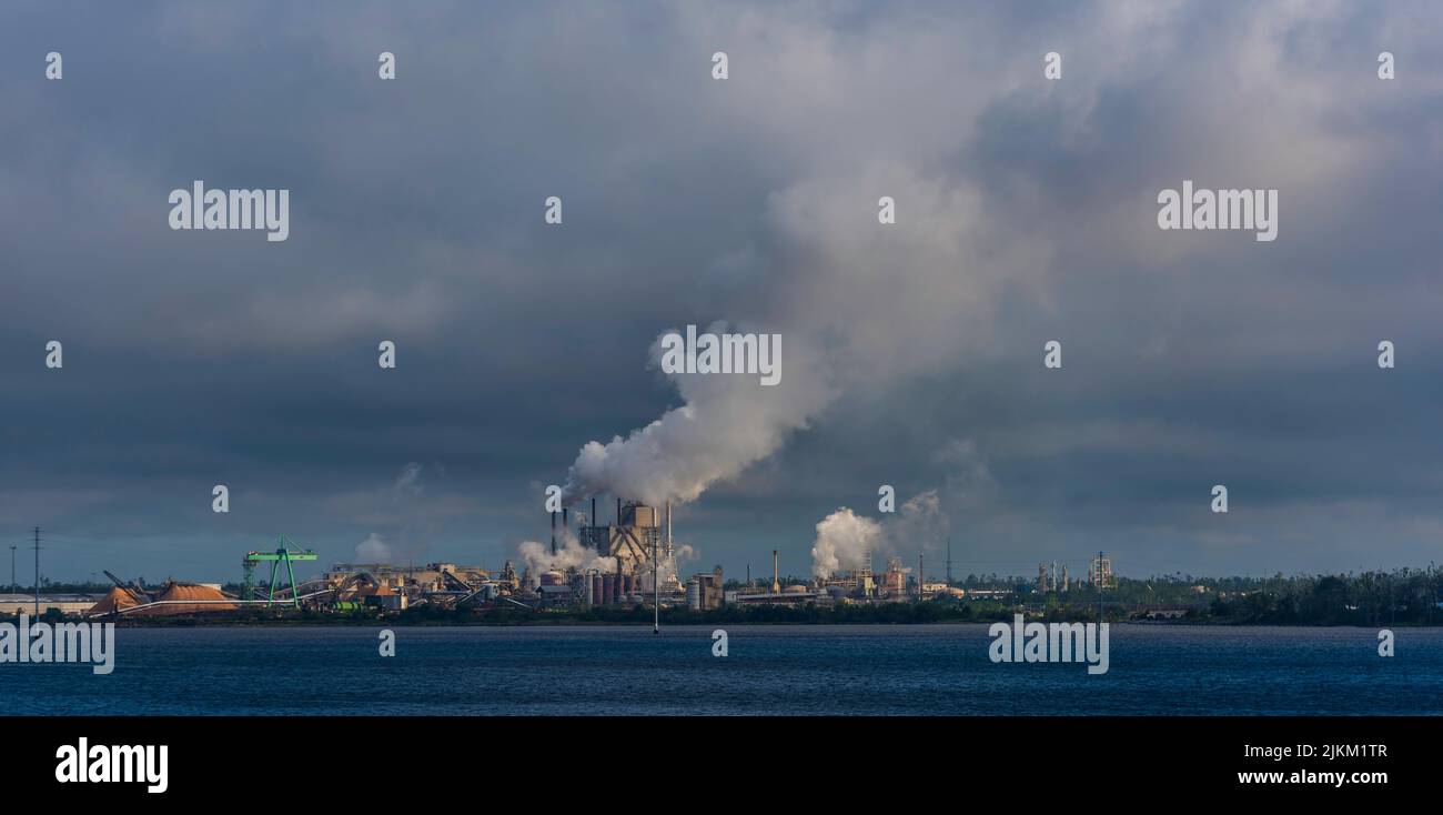 A factory with smoke coming out from industrial pipes captured from the sea Stock Photo