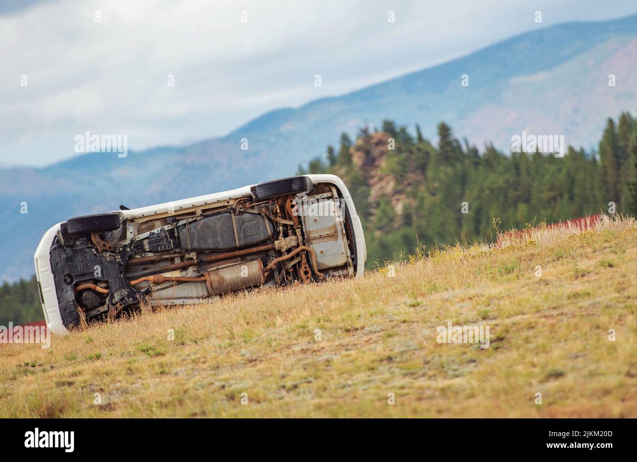 Crash Involved Rollover Car Out of Highway Laying on a Side Between Grasses. Stock Photo