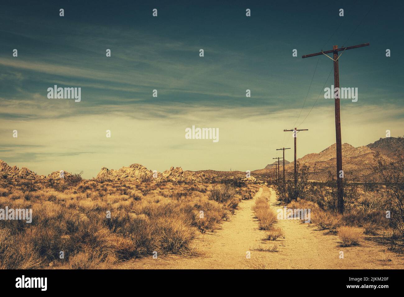 Mojave Desert Rural Sandy Road. Southern California Countryside Theme with Wooden Electric Poles. Stock Photo