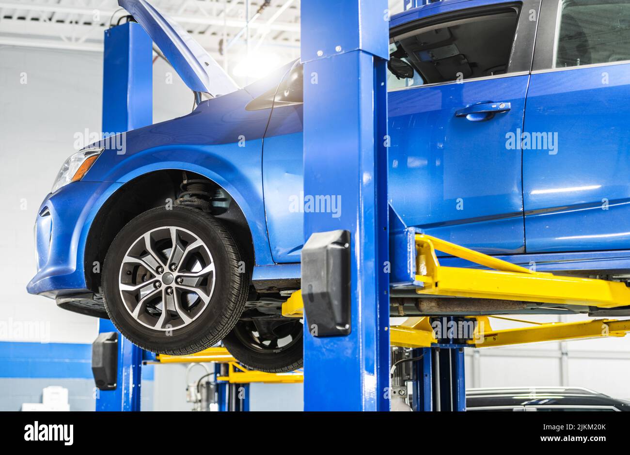 Automotive Industry Theme. Modern Blue Compact Car Maintenance on a Lift. Stock Photo