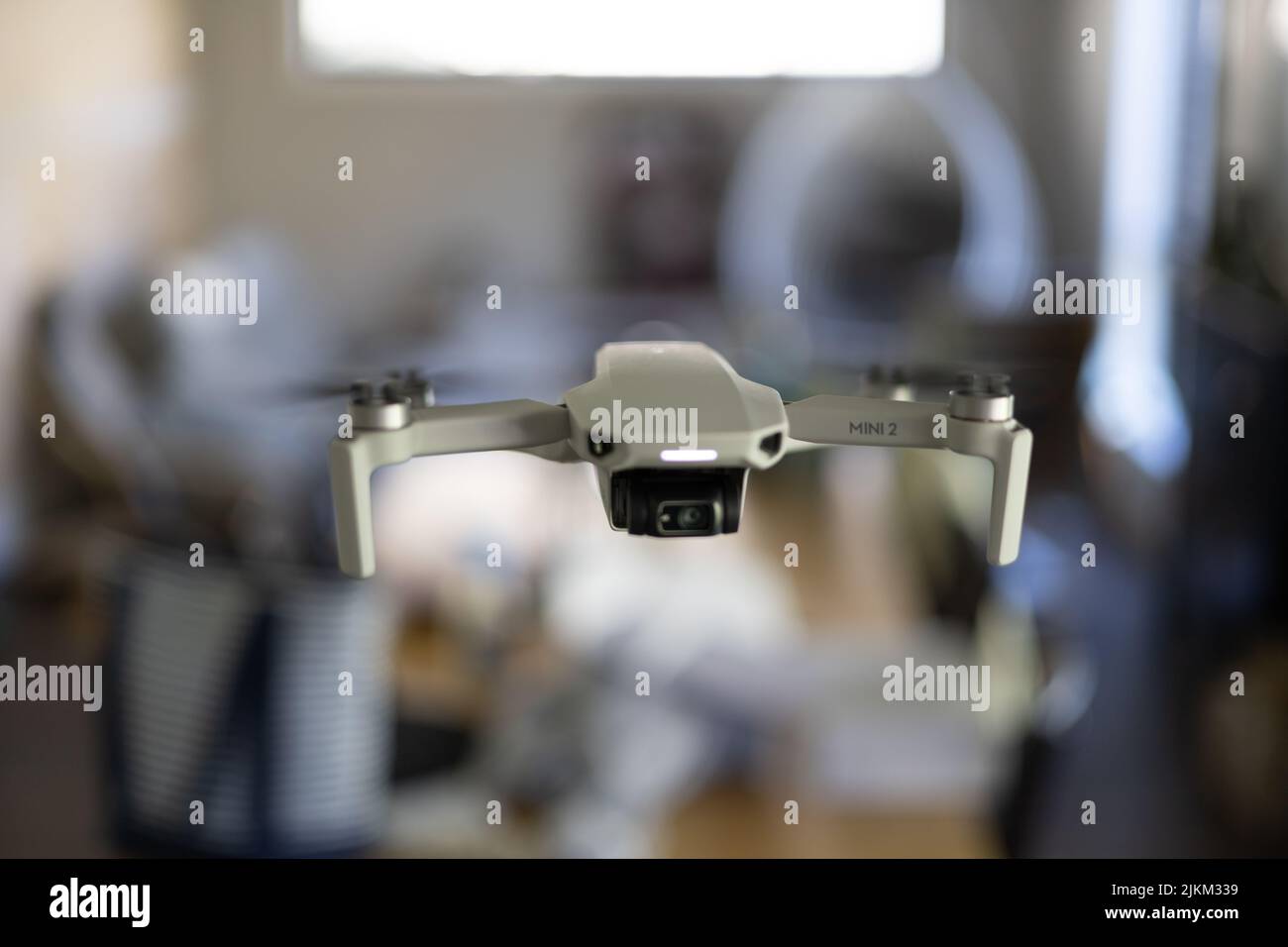 A DJI mini drone midair flying inside house with bokeh background Stock Photo
