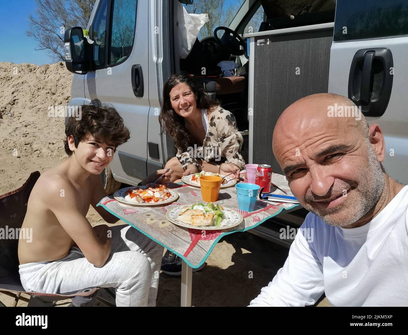 Family enjoying a meal outdoors in a motorhome Stock Photo