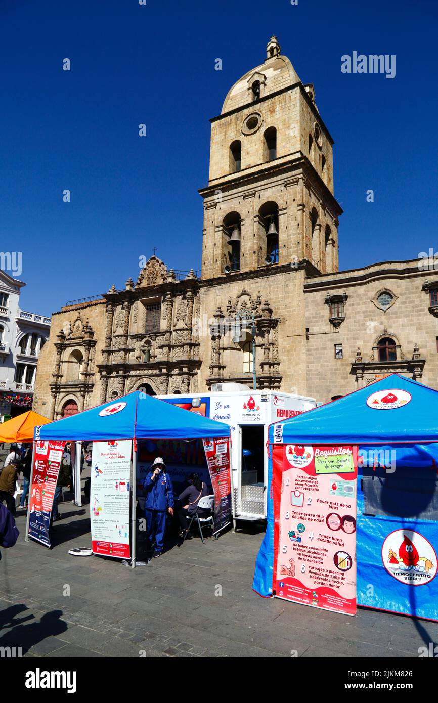 Plaza San Francisco, La Paz, Bolivia. 2nd August 2022. A doctor stands next to mobile collection centre where people can give blood, a service organised by the La Paz city health authorities. Bolivia's blood banks rely heavily on donations from volunteers and collection centres like this are common in the city, especially during holiday periods or when there are shortages. Behind is San Francisco church, the most important and impressive colonial church in the city. Stock Photo