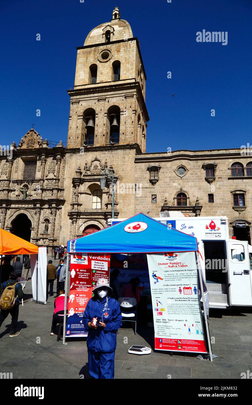 Plaza San Francisco, La Paz, Bolivia. 2nd August 2022. A doctor stands outside a mobile collection centre where people can give blood, a service organised by the La Paz city health authorities. Bolivia's blood banks rely heavily on donations from volunteers and collection centres like this are common in the city, especially during holiday periods or when there are shortages. Behind is San Francisco church, the most important and impressive colonial church in the city. Stock Photo
