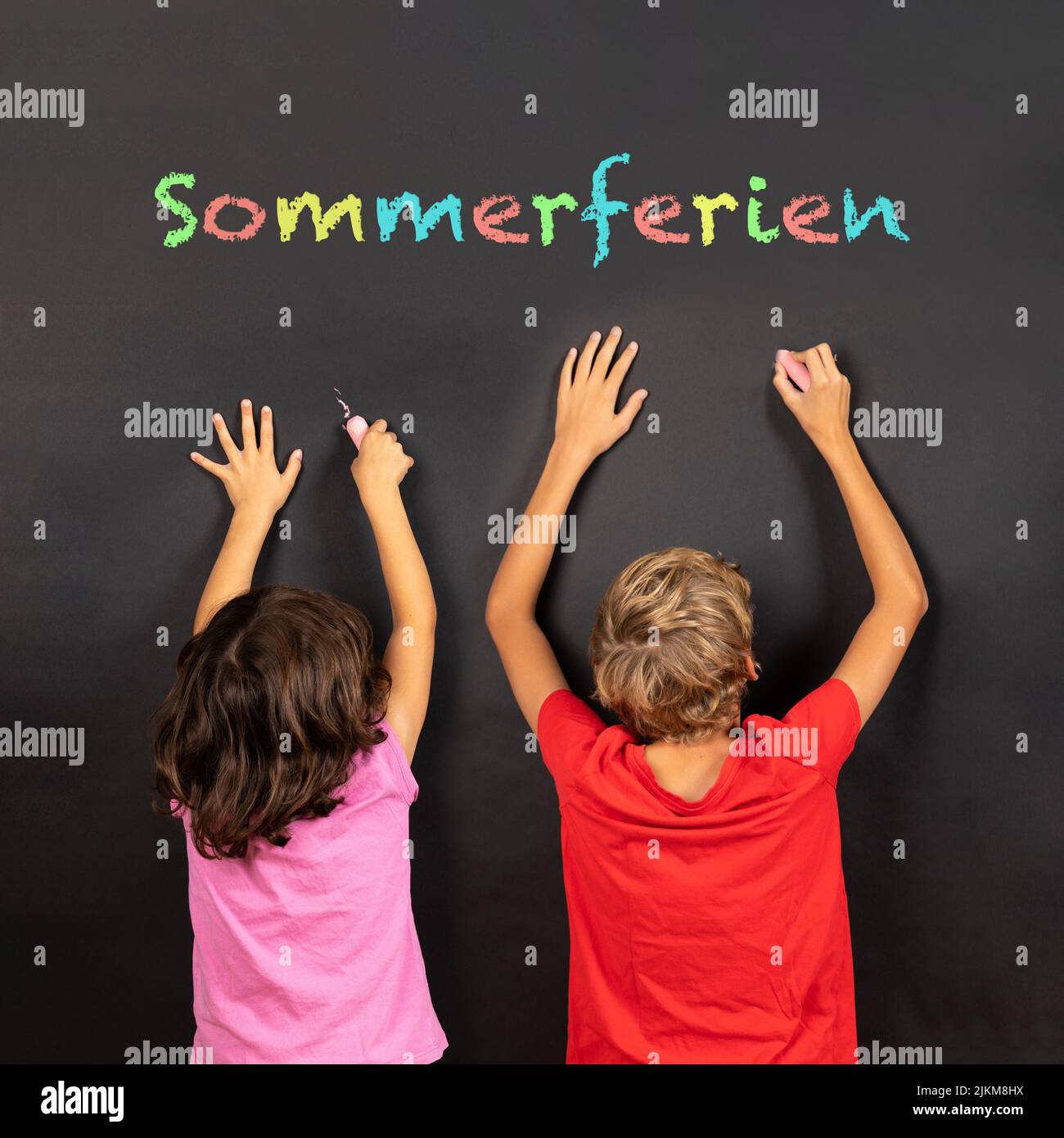 girl and boy writing on a blackboard with german text Sommerferien, in english summer holidays Stock Photo