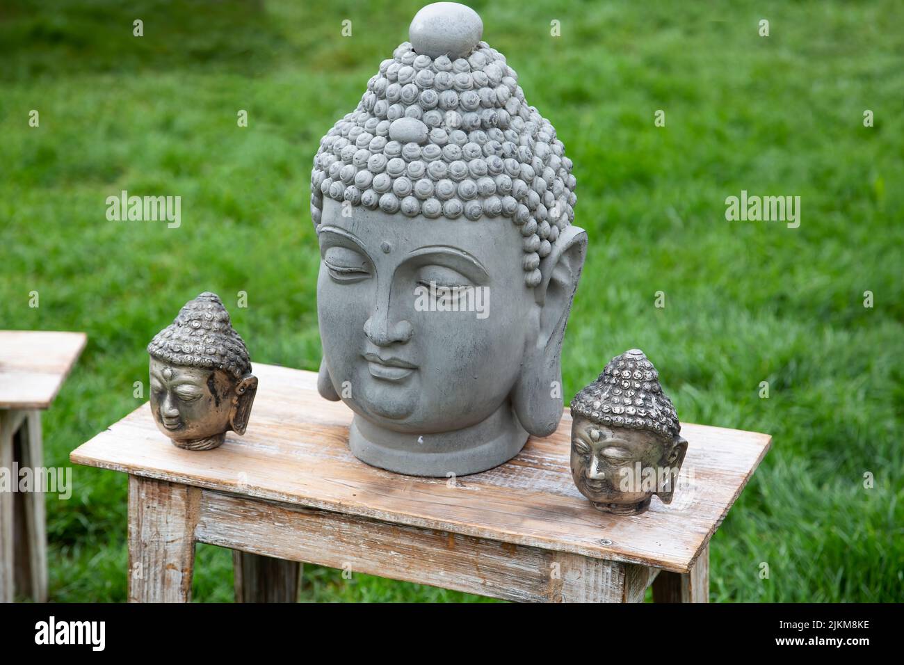 Stone heads of Buddha on a wooden table in the garden Stock Photo