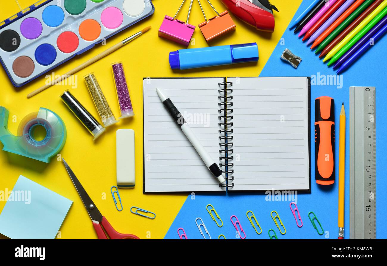 An open notebook with a pen and stationery on a yellow-blue background ...