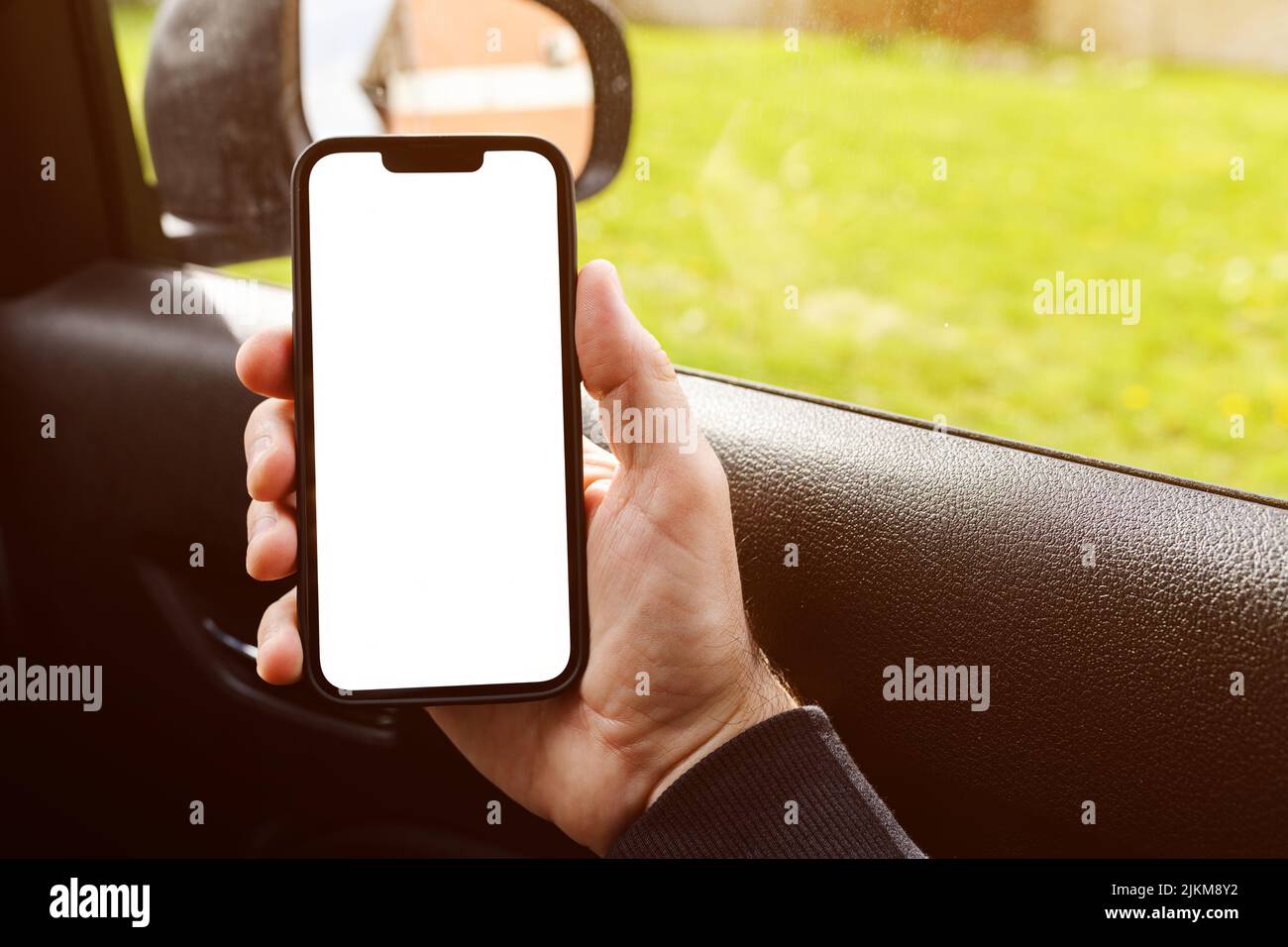 Male passenger in the car holding smartphone device with blank mockup screen as copy space Stock Photo