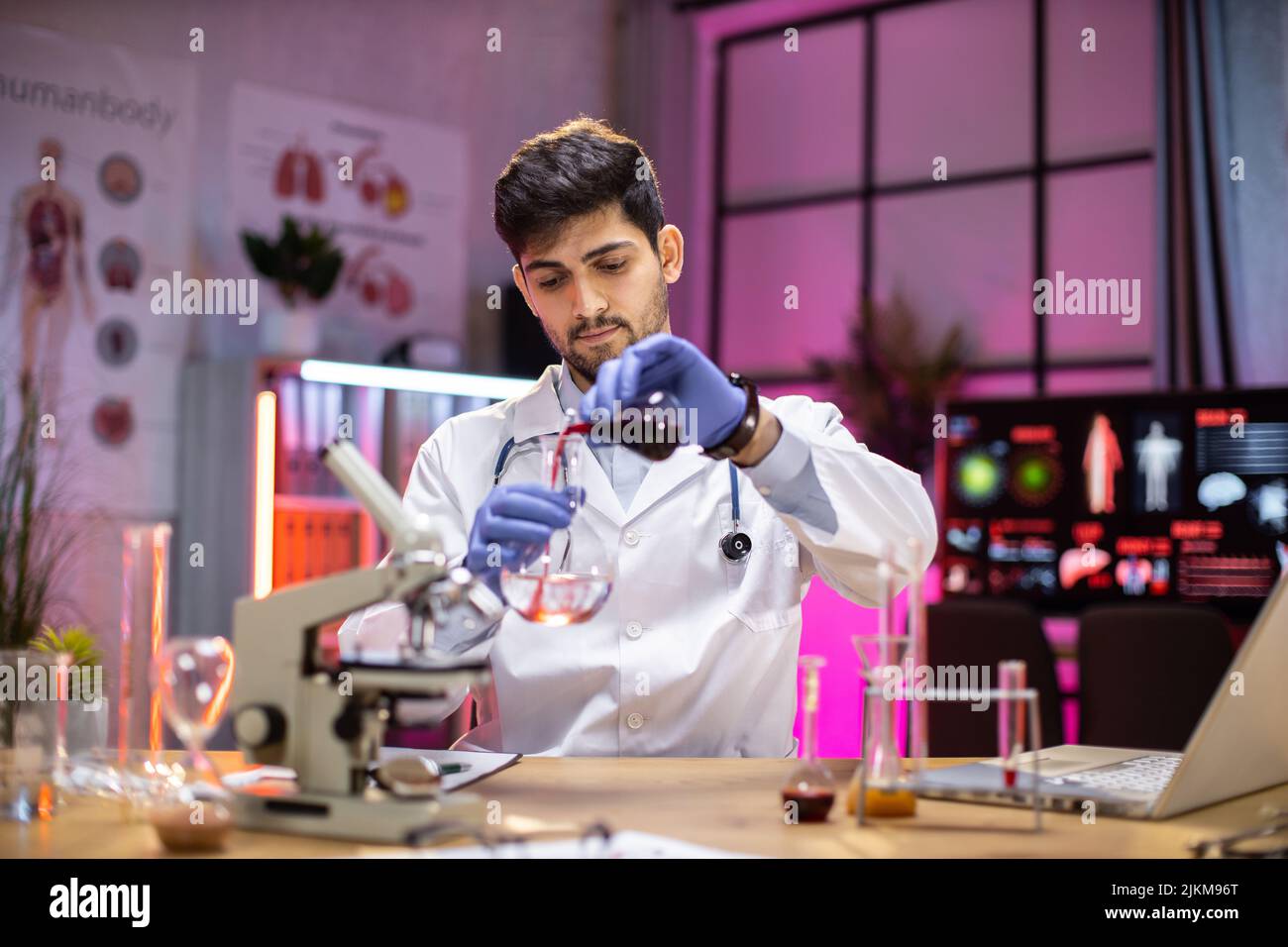 Male arab scientist working in modern lab. Doctor making microbiology research. Laboratory tools: microscope, test tubes, equipment. Coronavirus covid-19, bacteriology, virology, dna and health care. Stock Photo