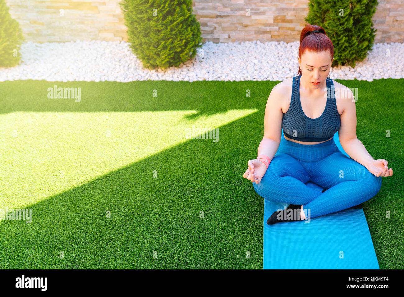 woman practicing meditation in the open air, relaxation exercises, doing the lotus posture. copy space. concept of health and well-being. Stock Photo
