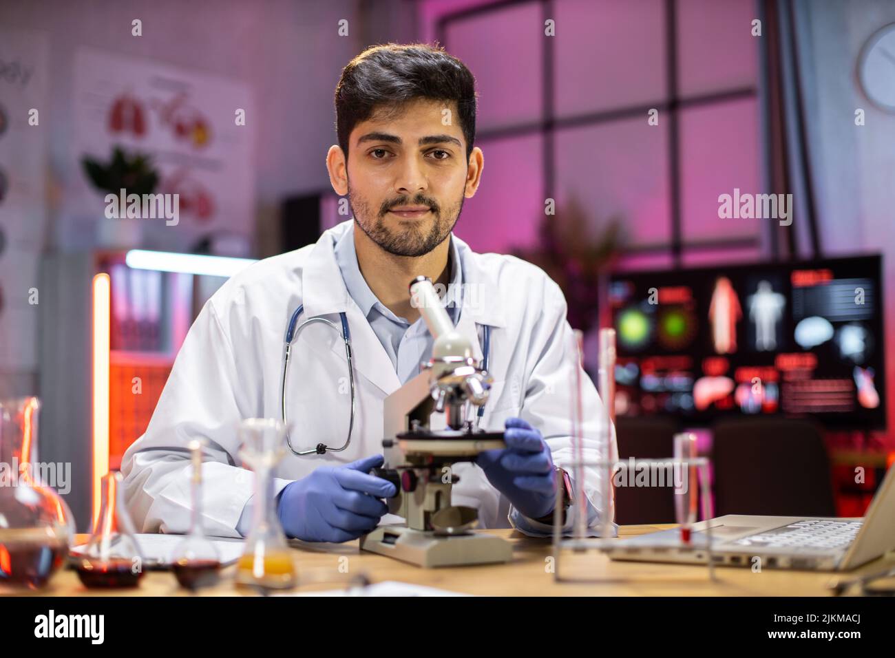 Modern medical research laboratory: portrait of scientist working, using microscope, analyzing samples. Advanced scientific pharmaceutical lab for medicine, biotechnology development. Stock Photo