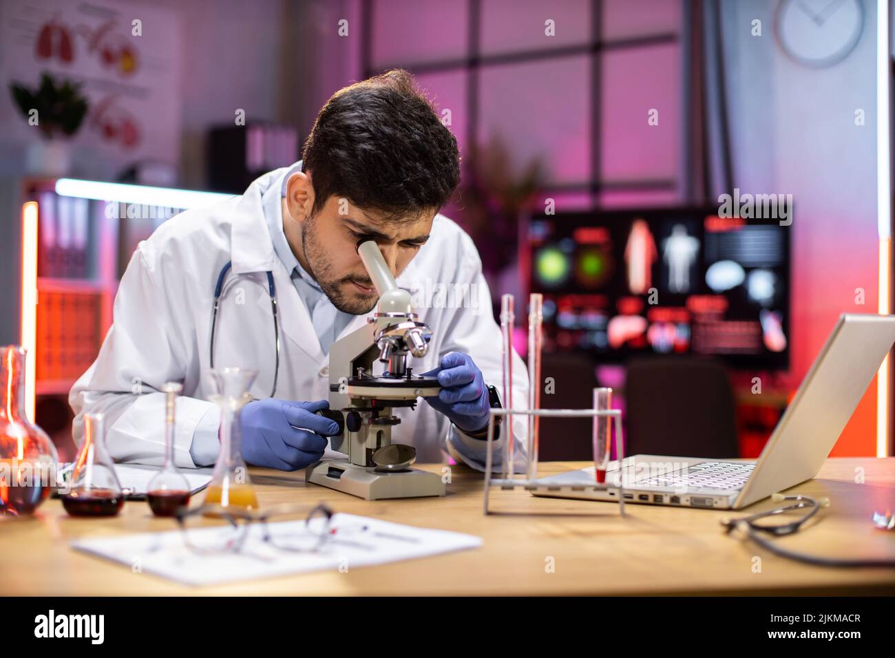 Modern medical research laboratory: portrait of scientist working, using microscope, analyzing samples. Advanced scientific pharmaceutical lab for medicine, biotechnology development. Stock Photo