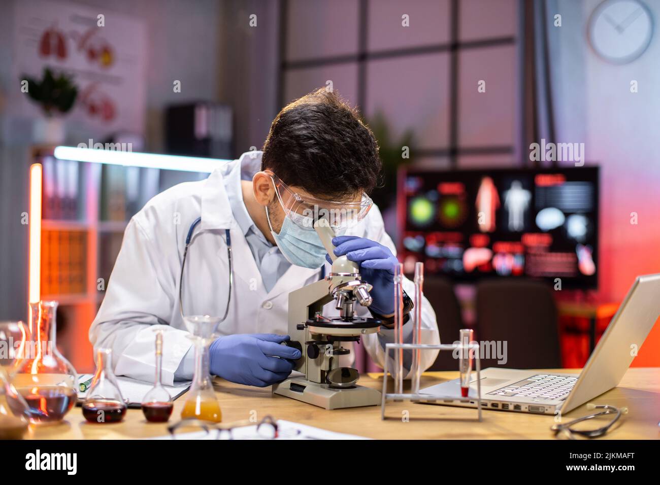 Modern medical research laboratory: portrait of scientist working, using microscope, analyzing samples. Advanced scientific pharmaceutical lab for medicine, biotechnology development. Stock Photo