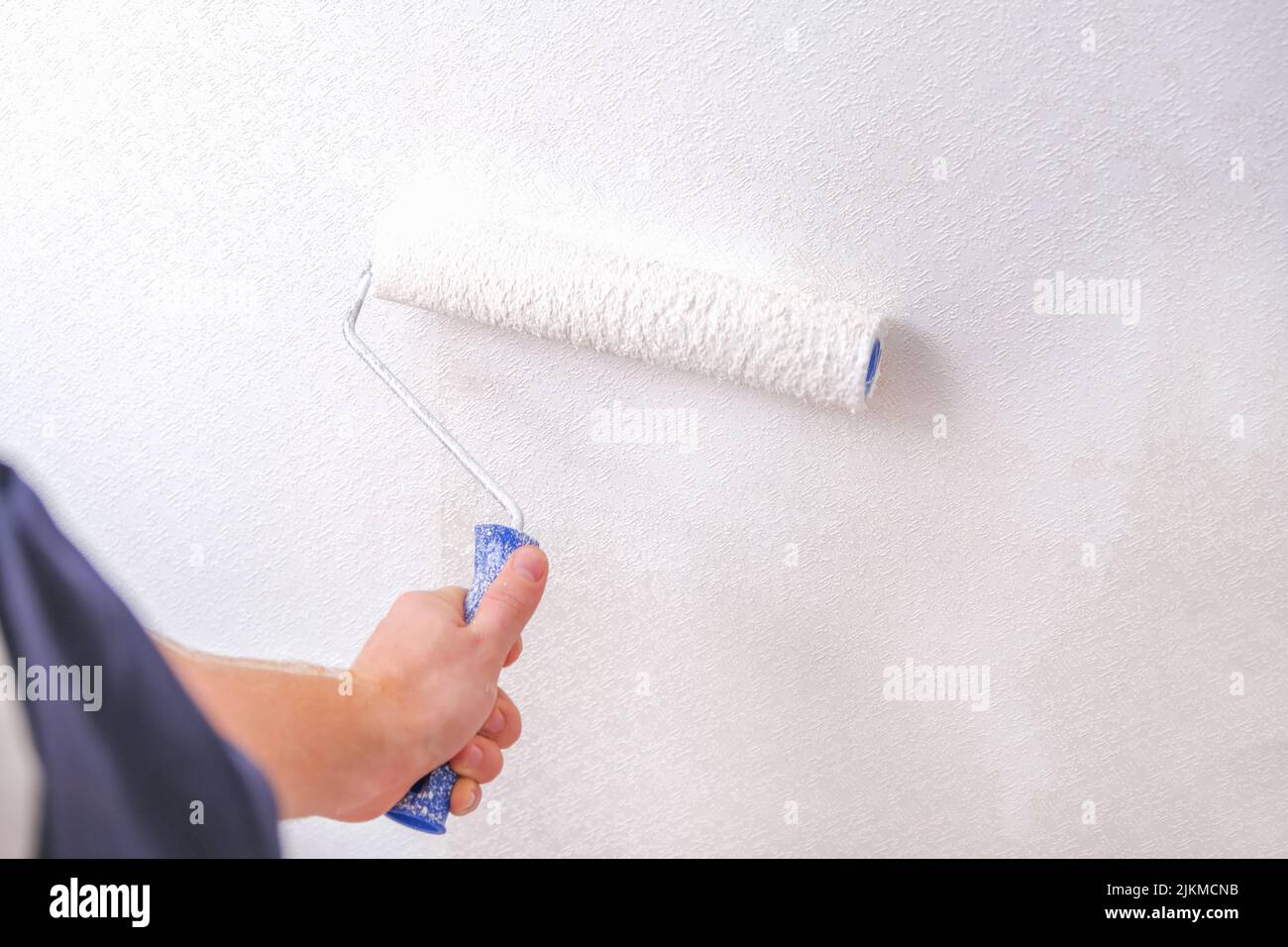 A man is painting vinyl wallpaper with a velour roller for painting