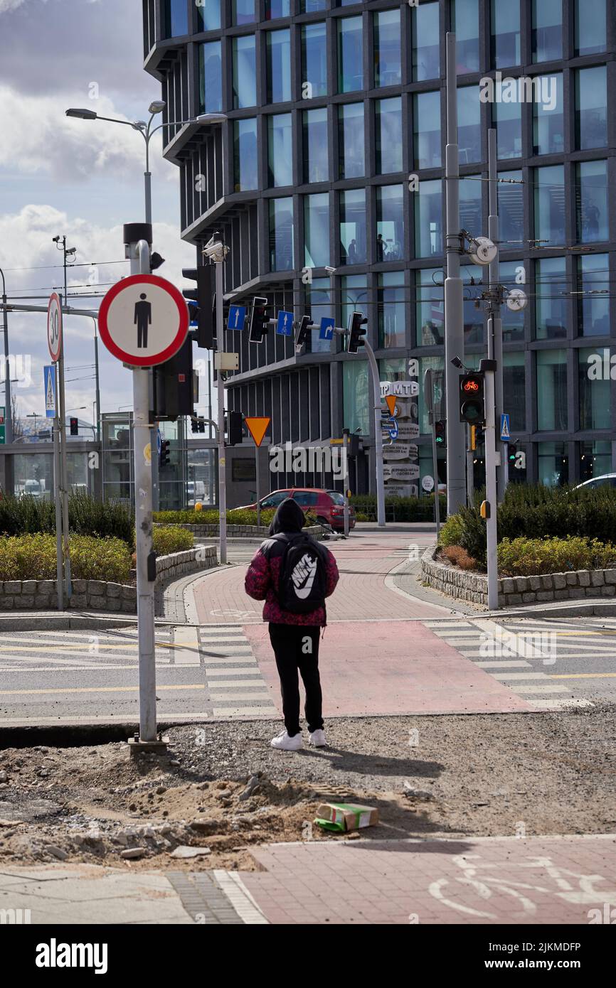A person waiting in front of red lights of a bike route crossing in the Kaponiera street in Poland Stock Photo