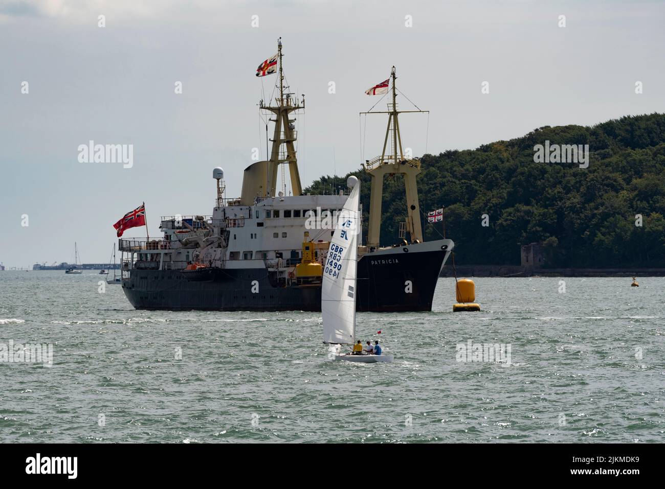 Cowes, Isle of Wight, England, UK.2022. Yacht sailing  past the Trinity House vessel Patricia during Cowes Week regatta. Stock Photo