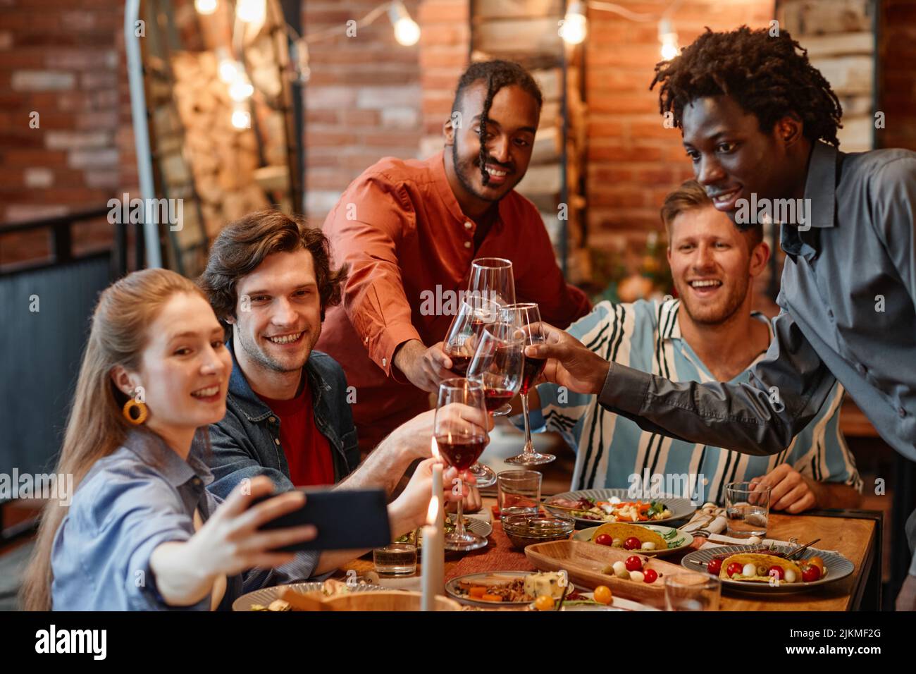 Diverse group of friends taking selfie photo at table during dinner ...