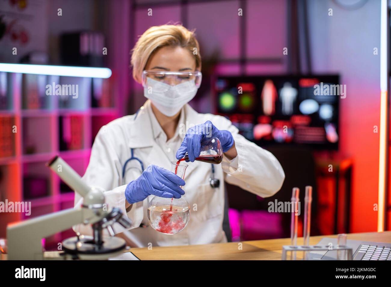 Female doctor microbiologist using microscope with vacuum tubes for samples with COVID 19 infection atypical pneumonia virus in laboratory. Stock Photo