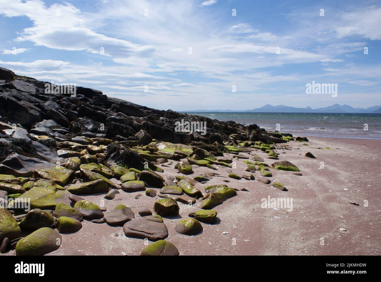 A dozen rocks covered in moss on a beach. Stock Photo