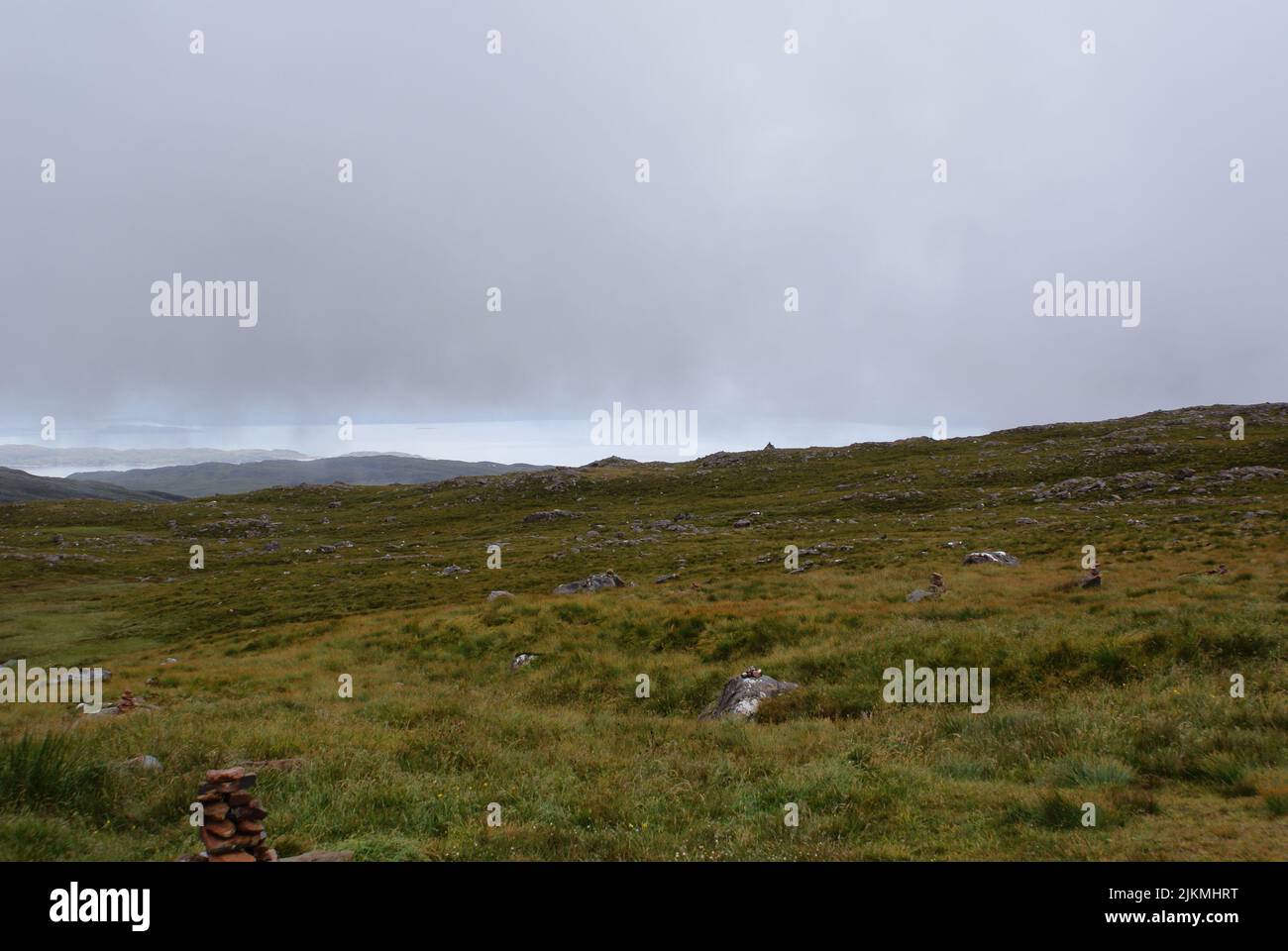 A pile of stones on a rock in a grassy terrain under a gloomy sky in Scotland Stock Photo