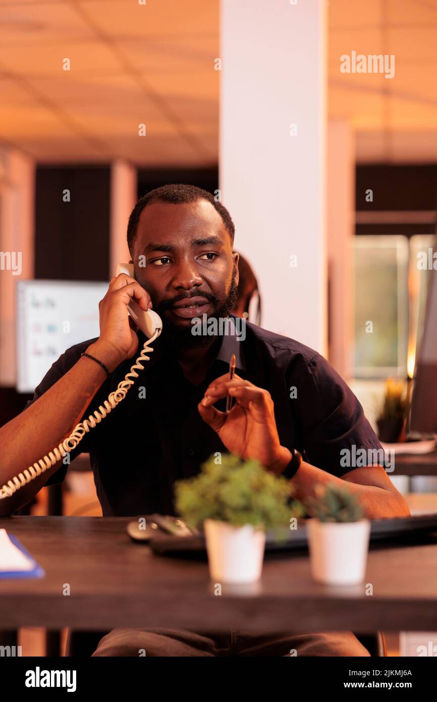 Male freelancer talking to people on landline phone, answering call to