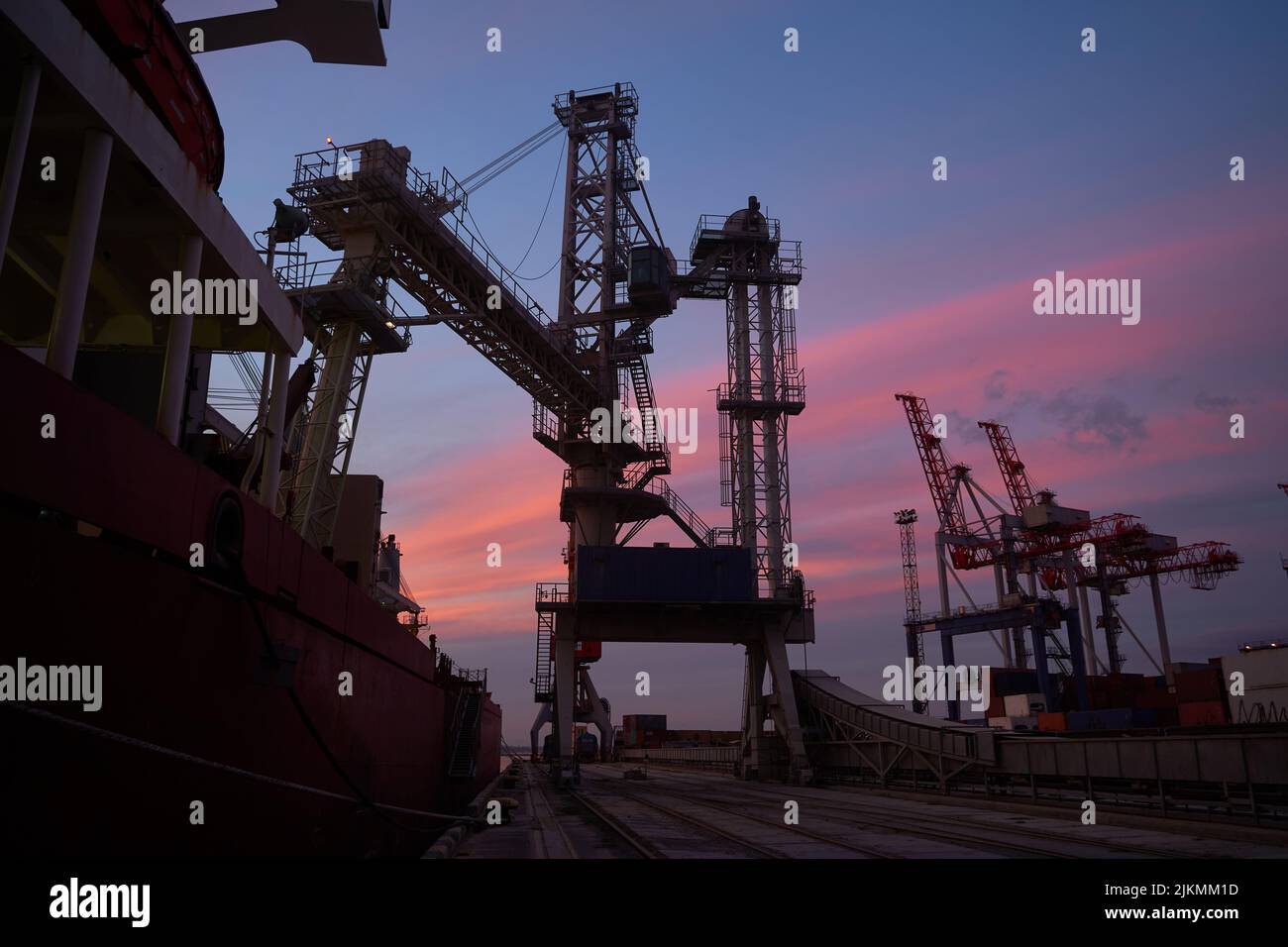 sunset in industrial landscape of commercial seaport. Sunset at seaport. Stock Photo