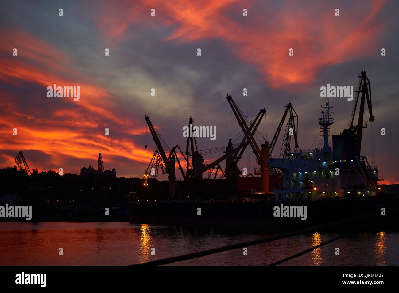 sunset in industrial landscape of commercial seaport. Sunset at seaport. Stock Photo