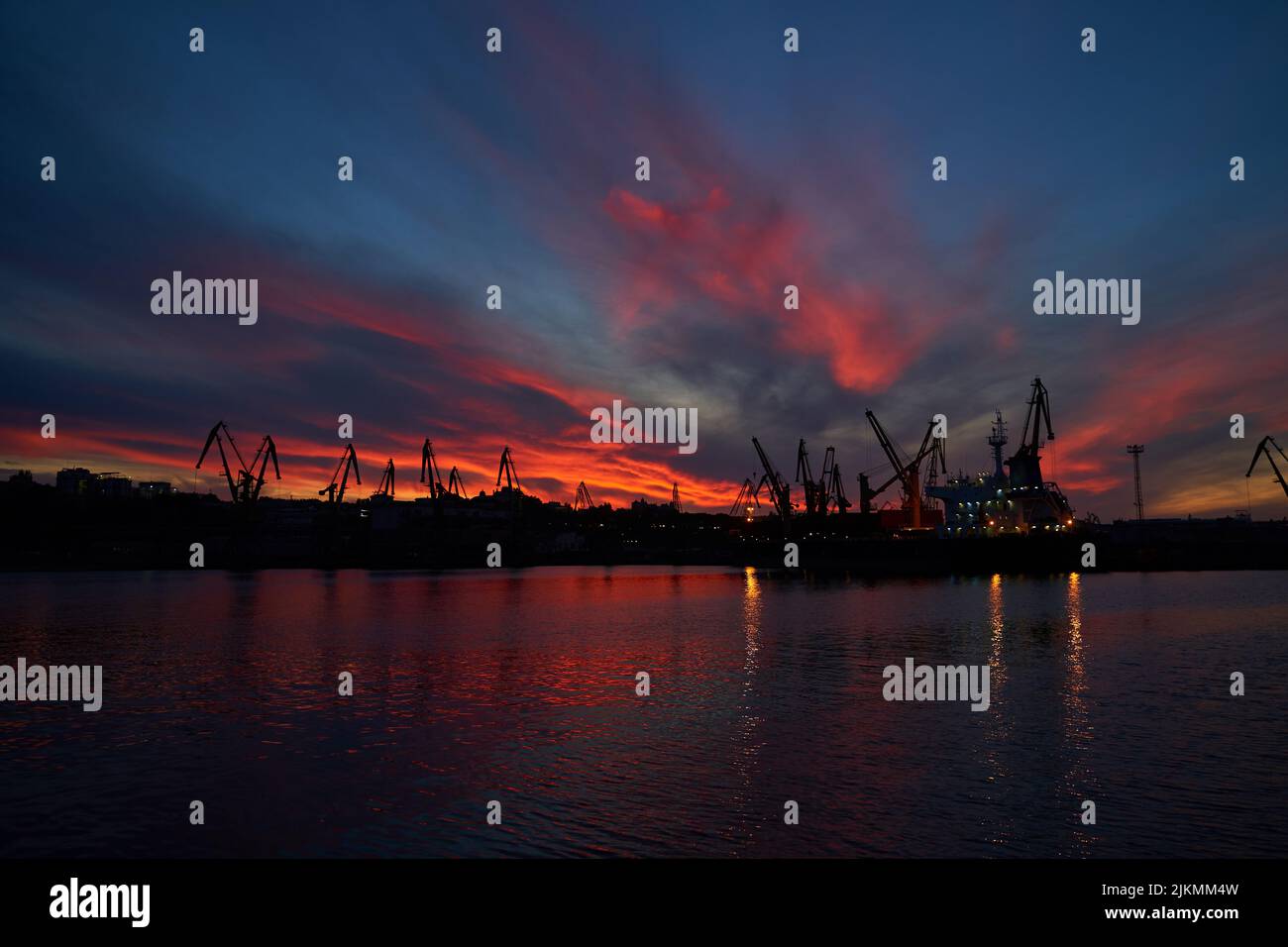 sunset in industrial landscape of commercial seaport. Sunset at seaport. Stock Photo