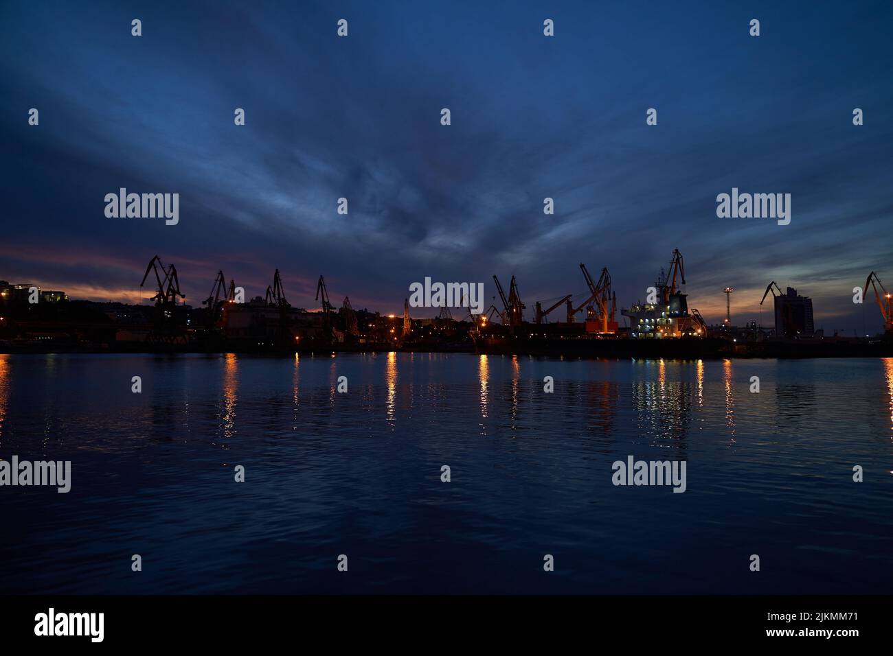 sunset in industrial landscape of commercial seaport. Sunset at seaport. Stock Photo