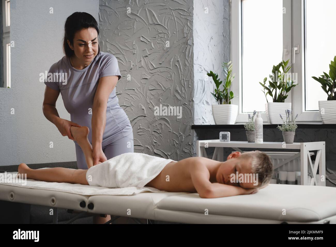 Child Foot massage treatment by professional massage therapist in clinic. Rehabilitation and kids healthcare concept. Physiotherapist working with Stock Photo