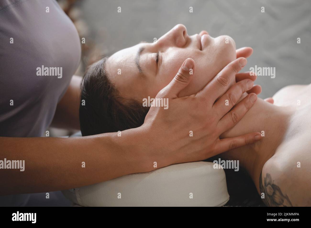 face massage with oil in traditional style made by professional beauty therapist women. anti-age massage Stock Photo