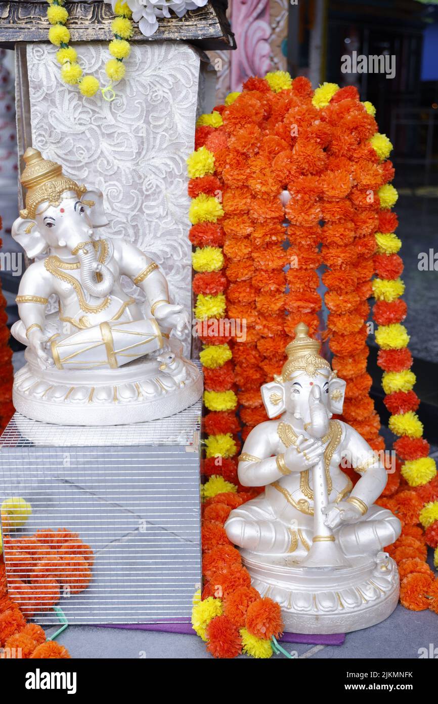 A vertical shot of sculptures of the God Ganesha (Vinayagar) and colorful garlands Stock Photo