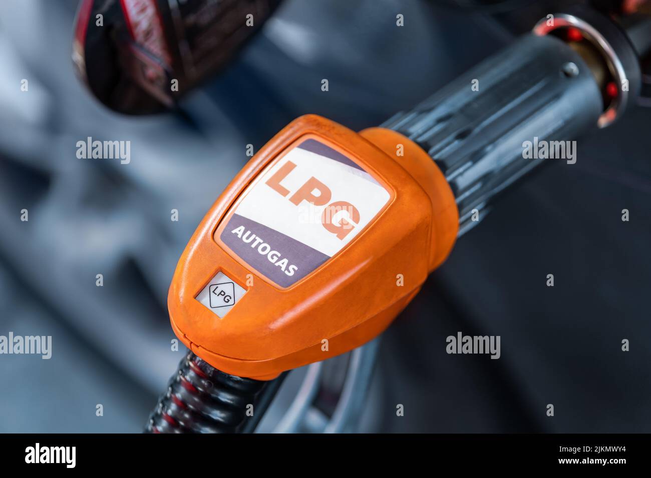 Close-up detail view of fuel autogas pump gun connected with noozle adapter to car tank to refill at car gas filling station. Refueling vehicle with Stock Photo