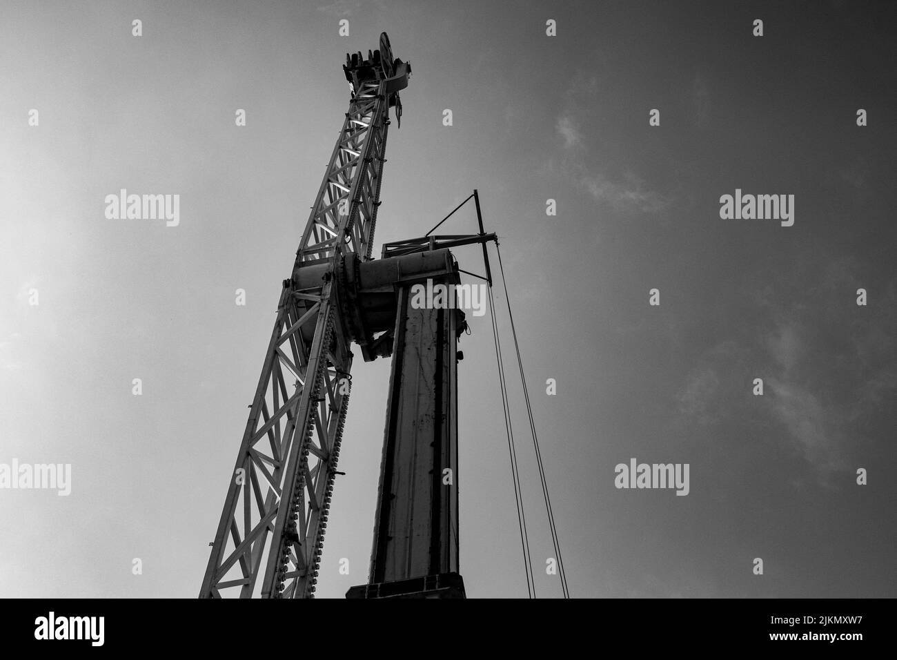A low angle shot of a Pile driver on the pier in a grayscale Stock Photo