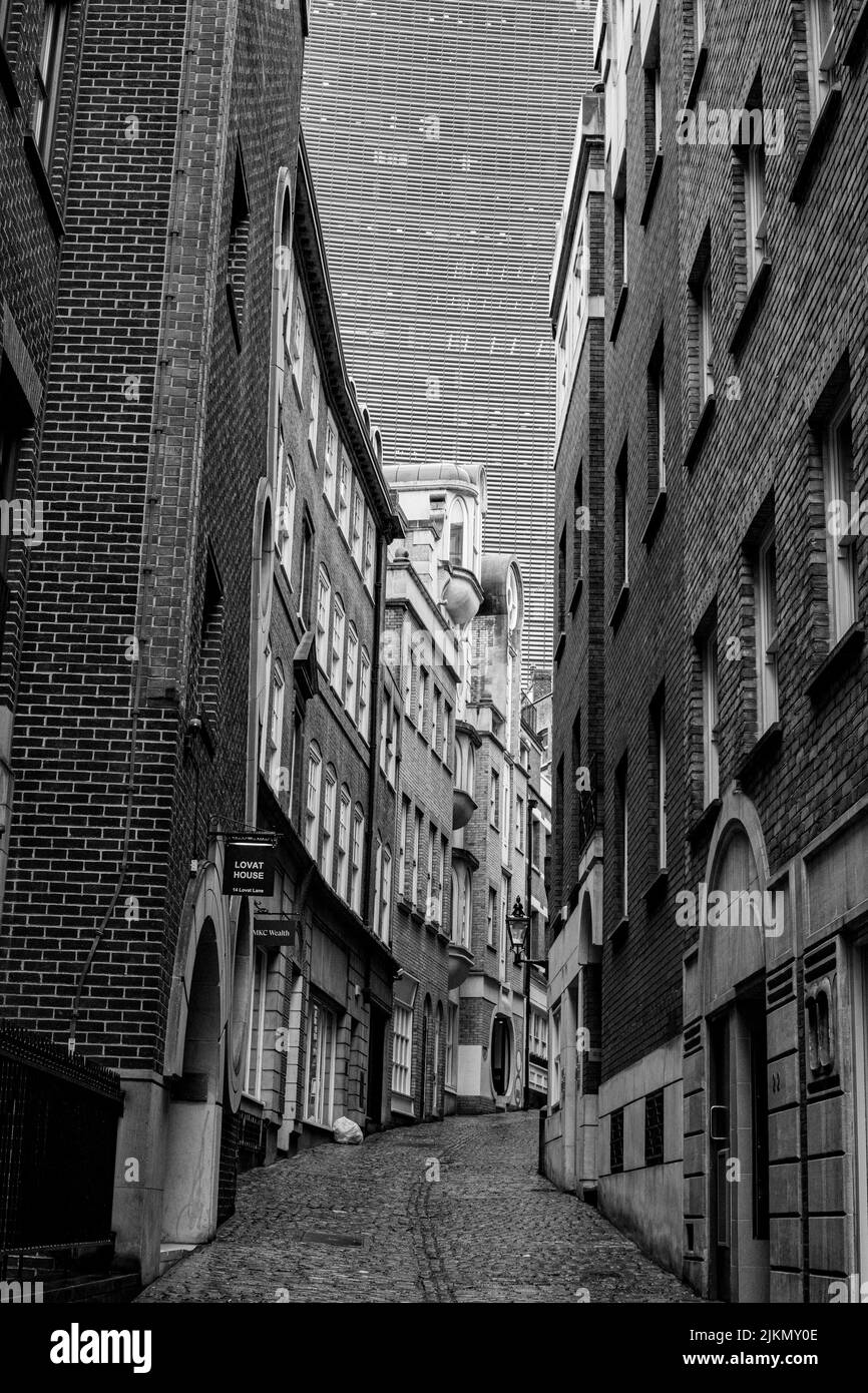 A grayscale shot of a London alleyway with a skyscraper in the background in London, UK Stock Photo
