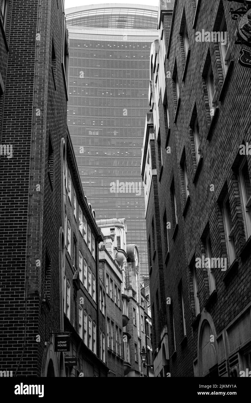 A grayscale shot of a London alleyway with a skyscraper in the background in London, UK Stock Photo