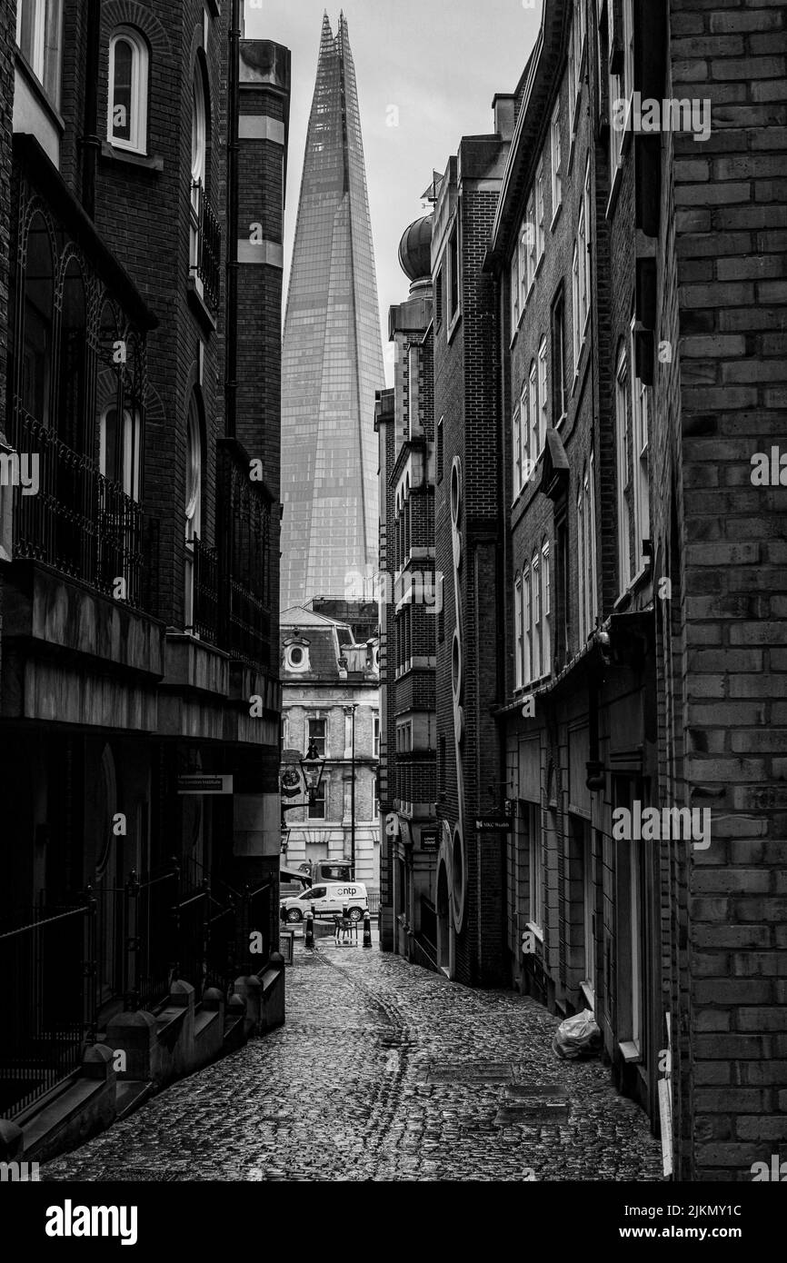 A grayscale shot of a London alleyway with a shard in the background in London, UK Stock Photo