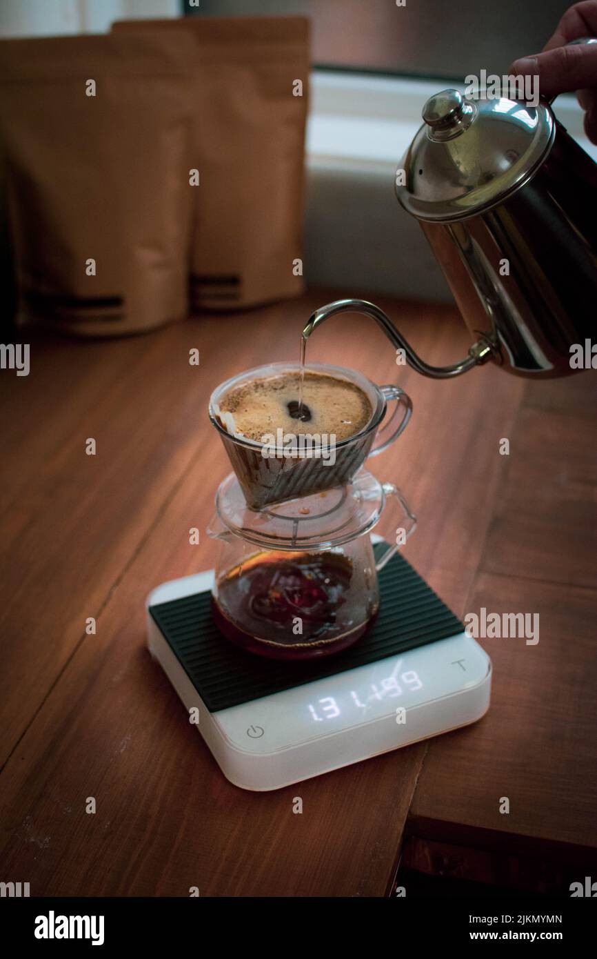 A vertical shot of a male pouring boiled water into the pour over