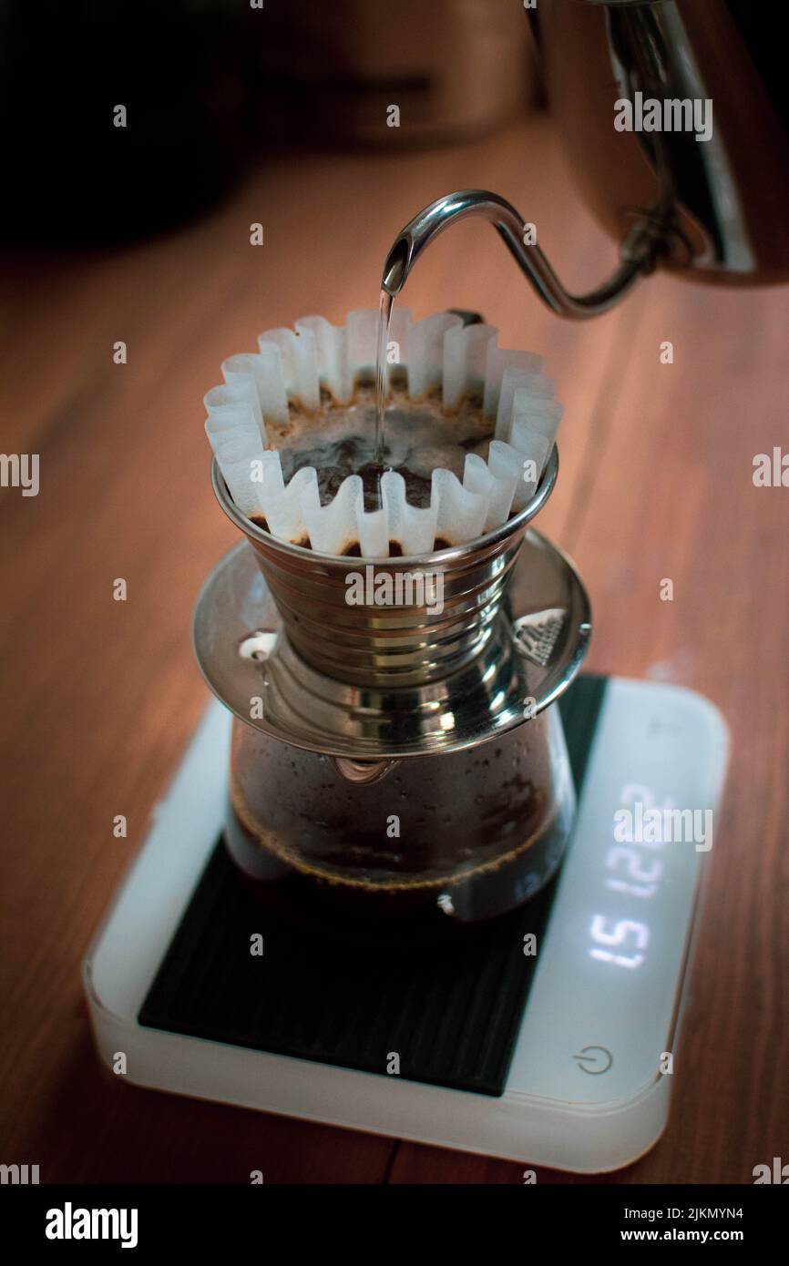 A vertical shot of a male pouring boiled water into the pour over