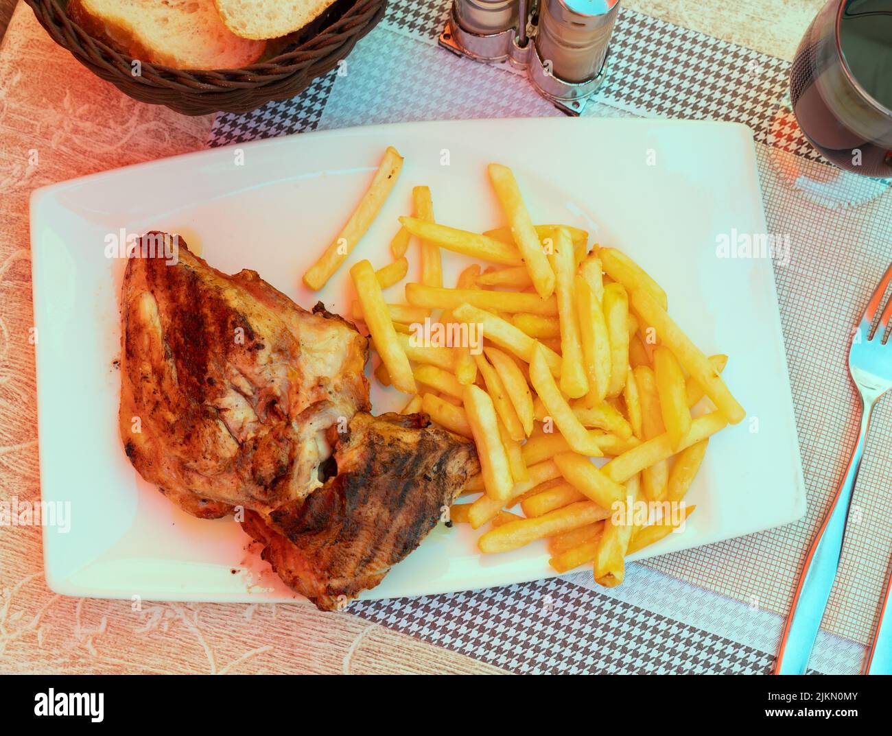 Baked chicken leg served on plate with side dish of fried potatoes