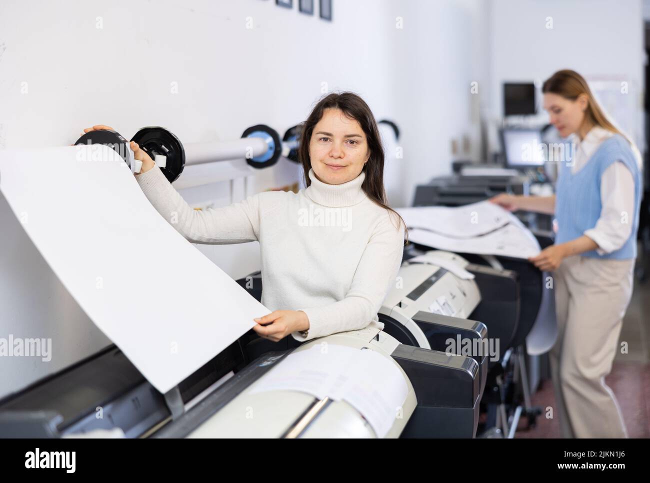 Print worker controlling printing process on modern offset machine in print shop Stock Photo