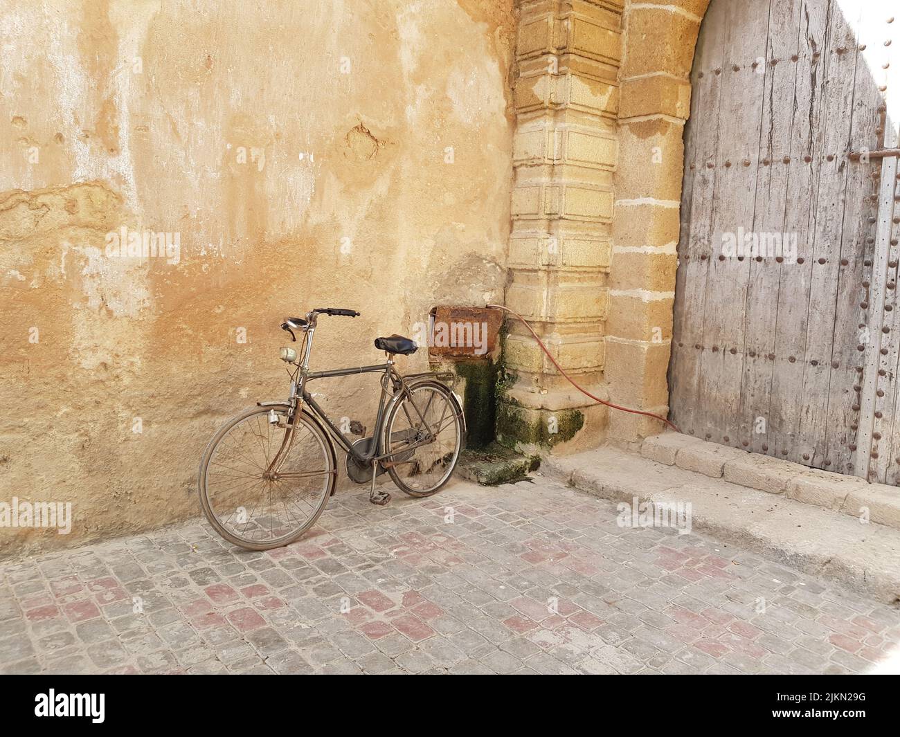 A view of an old bicycle parked near the wall in the street Stock Photo