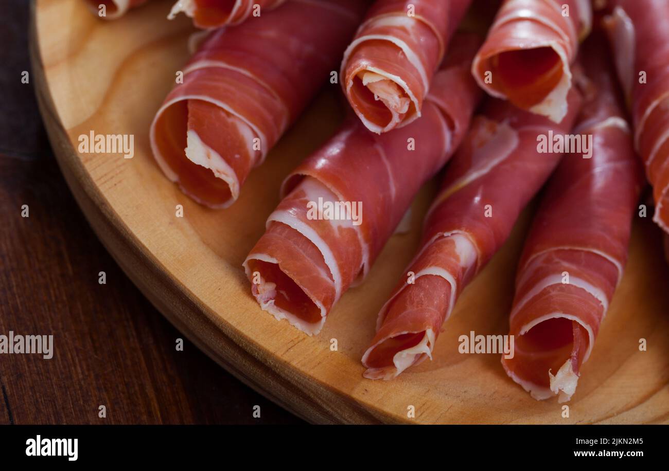 Spanish tasty meal rolls of prosciutto di parma at wooden desk Stock