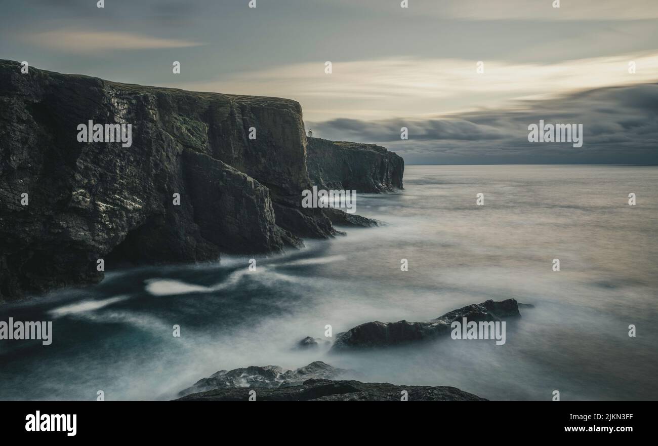 A scenic view of Eshaness Cliffs and Eshaness Lighthouse over the sea in Shetland, Scotland Stock Photo
