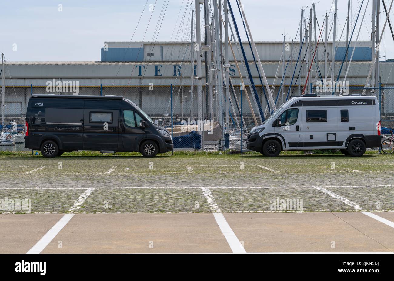 A side view of two - black and white mini buses parked in front of an industrial building Stock Photo